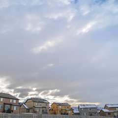 Fototapeta premium Frame Square Facade of houses with white wooden fences under blue sky with thick clouds