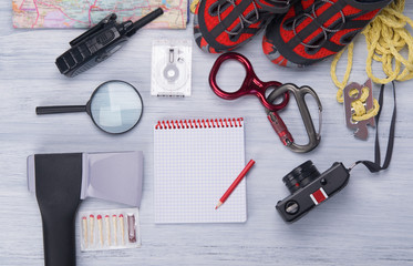 on a light background, a set for the traveler, ax, compass, rope, carabiner, magnifying glass, comfortable shoes, walkie-talkie, matches, camera ,map and notebook with pencil for records