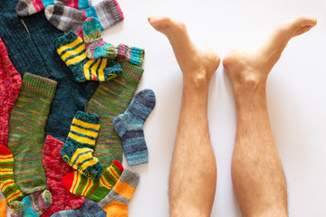 Colorful woolen socks and a pair of legs on white background