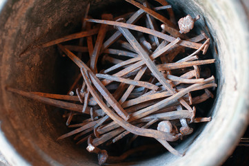 Very old rusty curved nails in the bucket