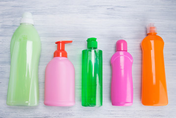 on a light background, multi-colored bottles with liquids for cleaning surfaces, washing dishes and...