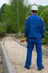 master in blue uniform, looking at the amount of work on the construction of roads, close-up, rear view