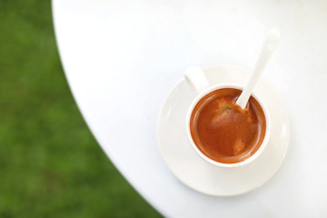 Overhead view of a freshly brewed mug of espresso coffee on white table