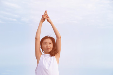 Woman is yoga by the sea on blue sky background