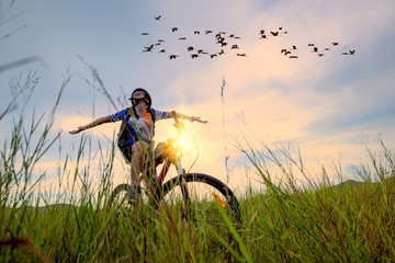 Woman cyclist bicycle cheerfully riding on the way of meadow field, adventure woman riding mountain bike alone in meadow at countryside
