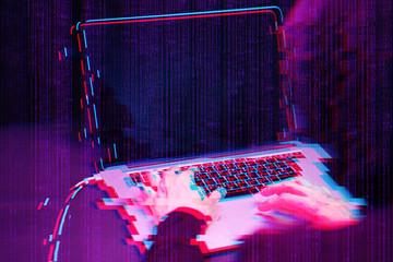 Hacker working with laptop in dark room with digital interface around. Image with glitch effect.