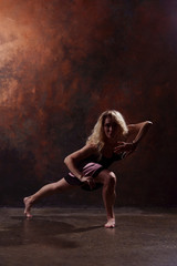 Obraz na płótnie Canvas Full-length photo of dancing blonde woman in black dress on brown background