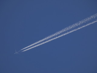 avión surcando el cielo azul y dejando una estela blanca