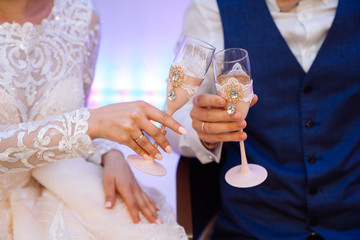 Close up glasses of champagne in hands of bride and groom in wedding day