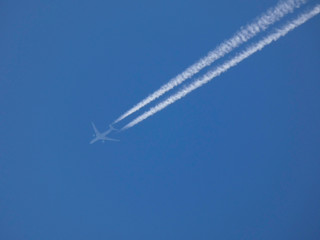 avión surcando el cielo azul y dejando una estela blanca