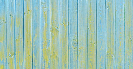 Natural wooden background. Surface of wooden texture for design and decoration. Shabby vertical boards with peeling paint. Blue and yellow color. Copy space.
