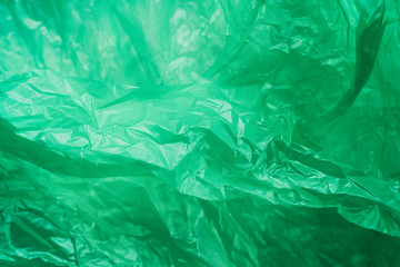 Green crumpled plastic bag texture background. Waste recycle concept. Polyethylene clear garbage bags.	