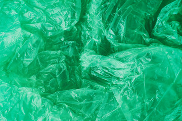 Green crumpled plastic bag texture background. Waste recycle concept. Polyethylene clear garbage bags.	