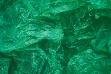 Green crumpled plastic bag texture background. Waste recycle concept. Polyethylene clear garbage bags. 