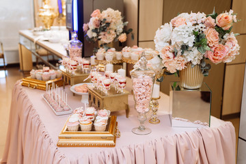 Candy bar on table in vase and plate, macaroon, marshmallow, cake and cupcake