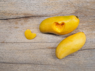 Top view Ripe Yellow Barracuda Mangos with slice shell shape heart on wood texture background.	