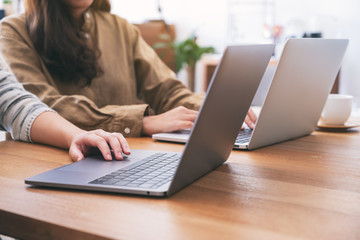 People using and looking at laptop computer on wooden table together