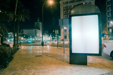 Blank advertisement on footpath with blurred traffic lights at night © Freepik