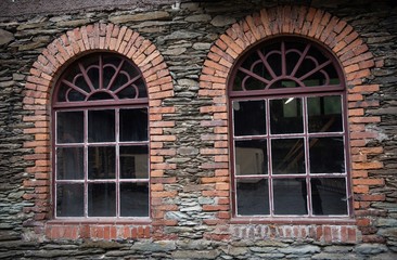 Fototapeta na wymiar Interessante, mit Backstein eingefasste Fenster einer alten stillgelegten Fabrikanlage