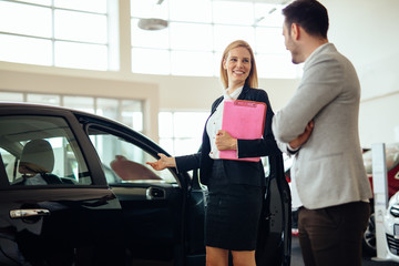 Fototapeta na wymiar Professional salesperson selling cars at dealership to buyer