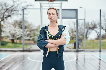 Beautiful and strong. Confident young disabled woman in sport wear keeping arms crossed while standing outdoors