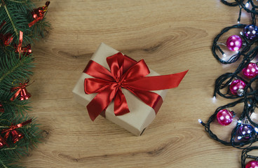 Christmas holiday Decoration; Christmas gift, fir tree branches and garland on wooden background. Flat lay, top view