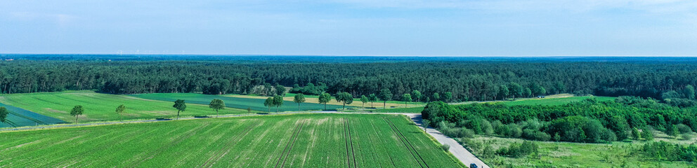 Fototapeta na wymiar Panorama from aerial photographs of arable land and meadows with a large forest area in the background, drone shot