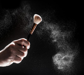 thick black brush in motion and loose powder particles scattered around