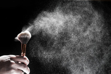 thick black brush in motion and loose powder particles scattered around