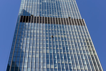 Fototapeta na wymiar Industrial climber washes glass on the facade of a skyscraper
