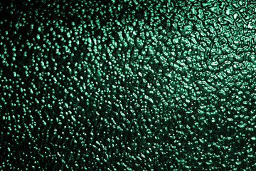 Fototapeta premium Abstract background of defocused mint green lights on dark background, glimpses of moon light on textured glass or water surface