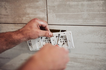 Electrician repairing / fixing wires in the wall.