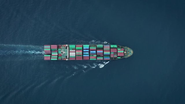 A cargo ship transports containers - motoring in ocean as seen from above. This particular vessel has just left port in Vietnam.