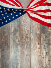 American flag lying on an aged, weathered rustic wooden background.