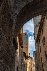 Fototapeta na wymiar Gasse mit Turm und Torbogen in San Gimignano Toskana Italien