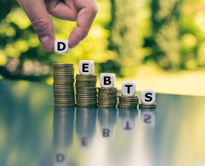 Symbol for decreasing debts. Dice form the word "depts" which are placed on declining high stacks of coins.