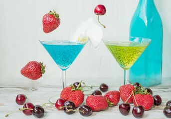 Refreshing healthy drink with chia seedsand falling strawberries and cherries. The atmosphere of summer and relaxation. Proper nutrition.