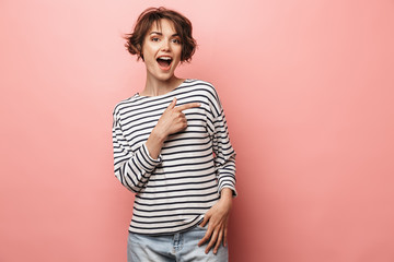 Obraz premium Excited shocked surprised beautiful woman posing isolated over pink wall background pointing.