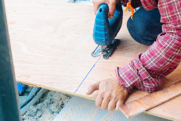 Close up Asian man carpenter using electric saws to cut large board of wood in a construction site. Male worker sawing board. Craftsman workshop routine. Handmade and craft furniture concept.