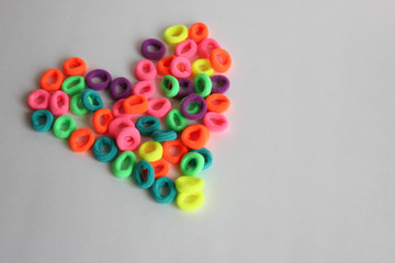  children's multi-colored hair ties on a white background in the shape of a heart