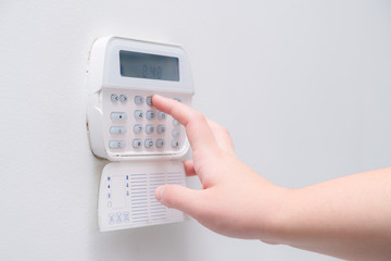 Woman hand entering alarm system password of an apartment, house of business office. Surveillance and protection console against rubbery and thief