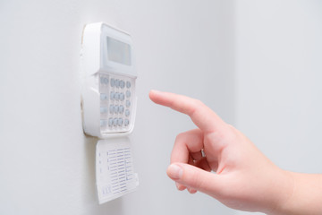 Woman hand entering alarm system password of an apartment, house of business office. Surveillance and protection console against rubbery and thief