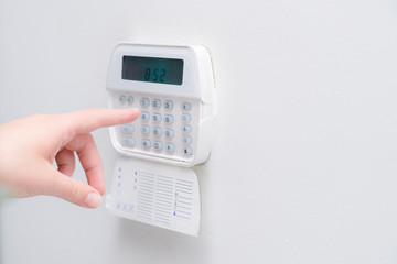 Woman hand entering alarm system password of an apartment, house of business office. Surveillance and protection console against rubbery and thief