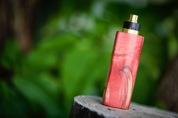 high end red and natural stabilized wood box mods with gold and black rebuildable dripping atomizer, vaporizer equipment, selective focus