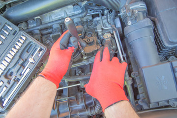 Close up hands of unrecognizable mechanic doing car service and maintenance