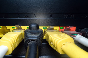 Multicolored network cables inserted in the router panel on a dark background. Internet connection,...
