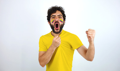 Sport fan screaming for the triumph of his team. Man with the flag of Ecuador makeup on his face...
