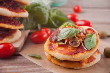 Homemade mini pizza on the wooden background.