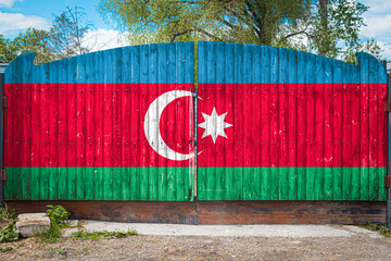 Close-up of the national flag of Azerbaijan on a wooden gate at the entrance to the closed territory on a summer day. The concept of storage of goods, entry to a closed area, tourism in Azerbaijan