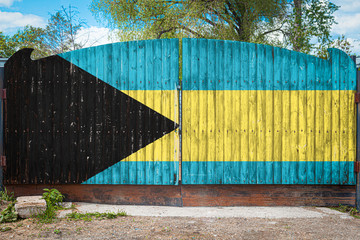 Close-up of the national flag of Bahamas on a wooden gate at the entrance to the closed territory on a summer day. The concept of storage of goods, entry to a closed area, tourism in Bahamas